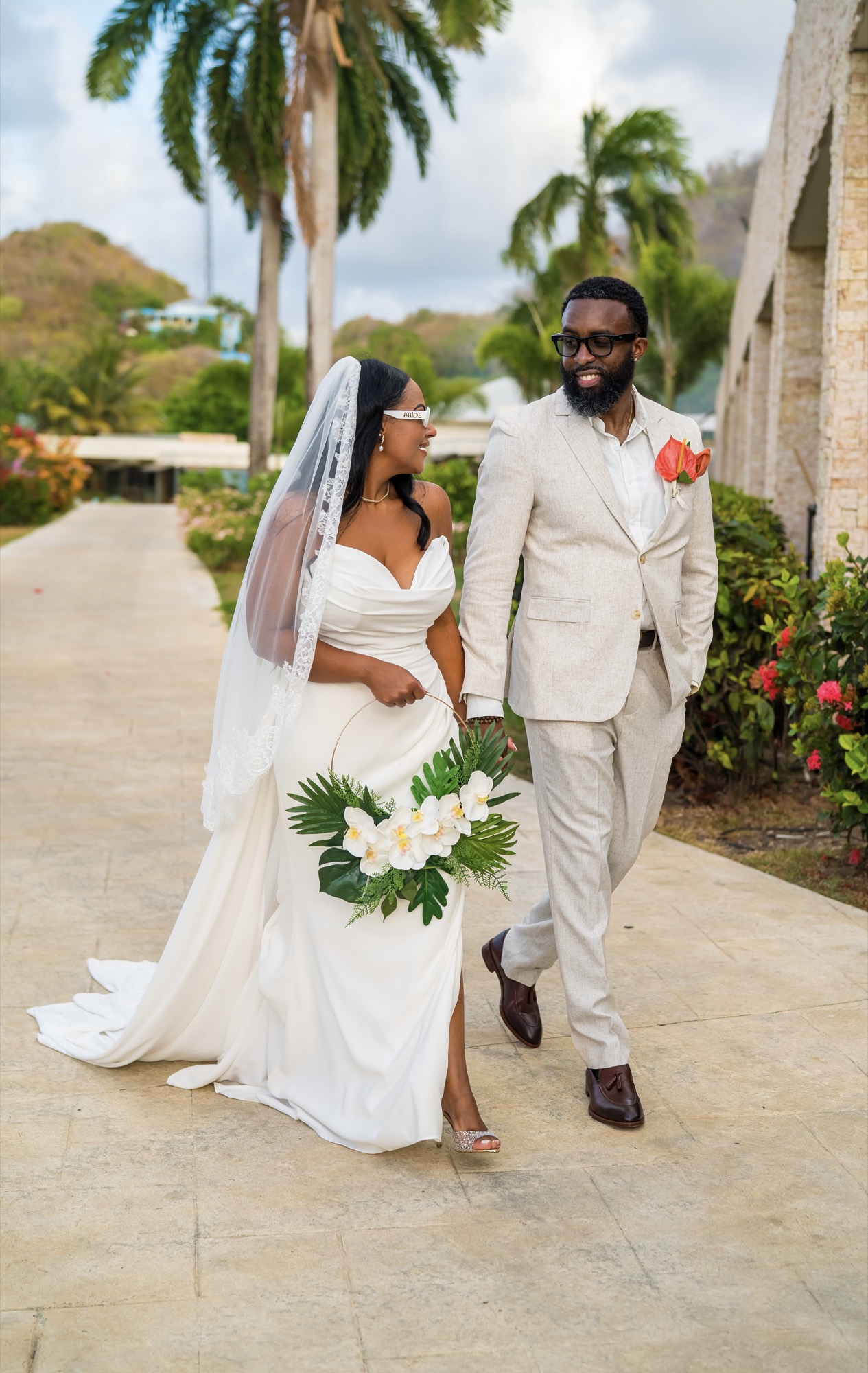A bride and groom walking together, her veil trailing behind them