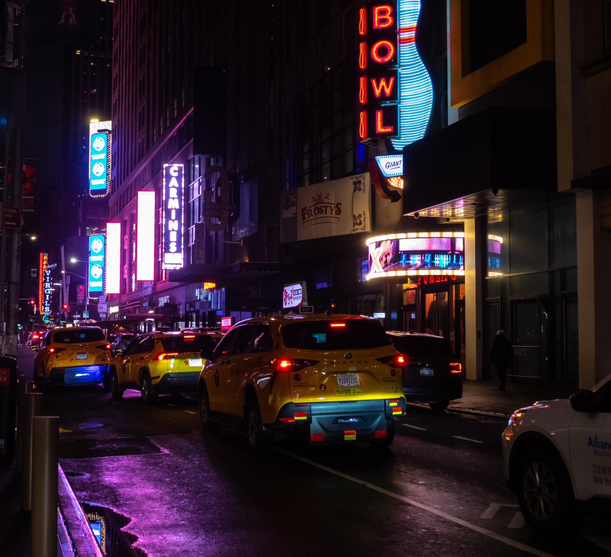 Yellow taxis under neon signs on 44th Street at night