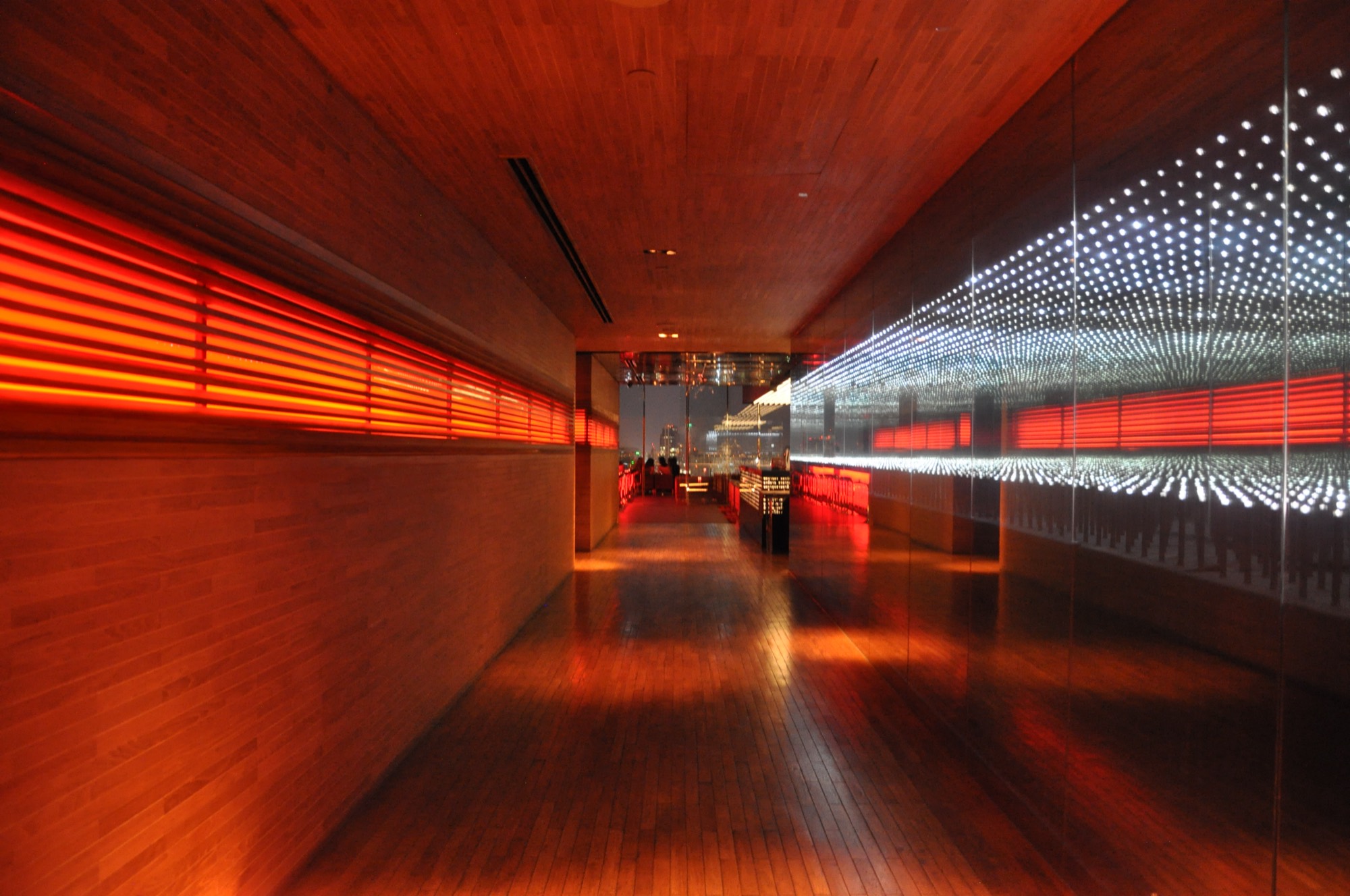 A long private room glowing red under string lights